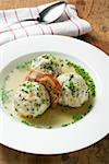 Clear broth with bacon dumplings in soup plate