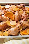 Roast chicken pieces with oranges on baking tray