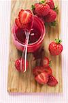 Jar of strawberry jam & fresh strawberries on chopping board