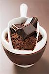 Pieces of chocolate and cocoa powder in scoop and bowl