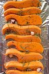 Pumpkin slices with rosemary and garlic on aluminium foil