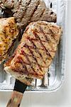 Grilled meat in aluminium grill tray (overhead view)