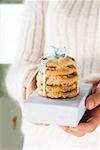 Hands holding cranberry cookies on small box