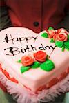 Person holding heart-shaped birthday cake with marzipan roses