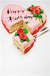 Pink heart-shaped birthday cake with piece on server