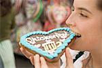 Frau beißt in Lebkuchen Herz (Oktoberfest, München)