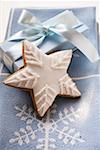 Gingerbread star with white icing in front of gift
