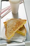 Geröstete Käse-Sandwiches auf Papier Serviette, Pappbecher, Strohhalme