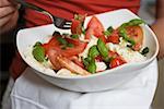 Woman eating tomatoes with mozzarella and basil