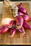 String of red onions on chopping board