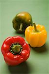 Three peppers (yellow, red, green) on green background