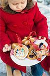 Small girl holding plate of baked tree ornaments