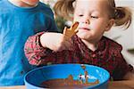 Girl dipping Christmas biscuit in chocolate icing