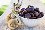 Chestnuts in white bowl on wooden table