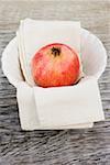 Pomegranate on cloth in white bowl