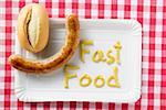 Sausage with bread roll and 'Fast Food' written in mustard