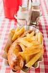 Sausage with ketchup & curry powder & chips in paper dish in restaurant