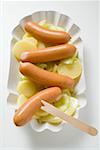 Frankfurters with potato salad in paper dish