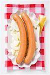 Frankfurters with potato salad in paper dish, mustard