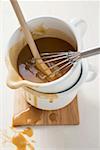 Gravy in an enamel jug with wooden spoon and whisk