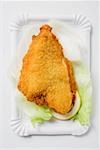 Breaded fish fillet on lettuce leaf and lemon