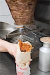 Hand holding döner wrap in a snack bar