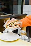 Hand putting a döner kebab on a plate in a snack bar