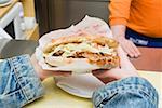 Mains tenant un döner kebab dans un snack-bar