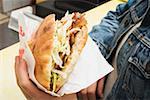 Mains tenant un döner kebab dans un snack-bar