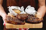 Homme tenant des steaks de bœuf grillé sur planche à découper