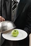 Butler serving apple on plate with dome cover