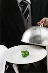 Butler serving fresh parsley on plate with dome cover