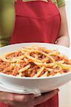 Woman holding bowl of macaroni with mince sauce