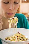 Young woman eating spaghetti with chillies