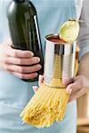 Frau hält Spaghetti, Zinn von Tomaten & Flasche Wein