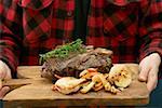 Man serving grilled T-bone steak on chopping board
