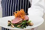 Chef serving beef fillet with green asparagus