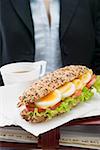 Woman holding sandwich and drink on organiser