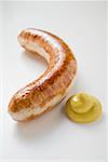 Sausage (bratwurst) with mustard on white background