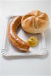 Sausage (bratwurst) with mustard & bread roll on paper plate