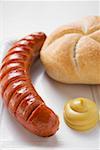 Sausage (bratwurst) with mustard & bread roll on paper plate