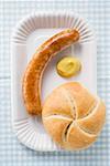 Sausage (bratwurst) with mustard & bread roll on paper plate