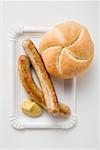 Sausages (bratwursts) with mustard & bread roll on paper plate