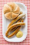 Sausages (bratwursts) with mustard & bread roll on paper plate