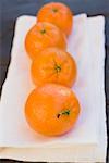 Four clementines on white cloth