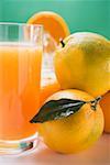 Glass of orange juice beside several oranges