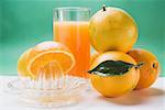 Glass of orange juice, several oranges and citrus squeezer