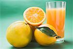 Glass of orange juice and several oranges