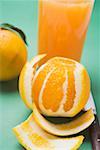 Peeled orange in front of glass of orange juice