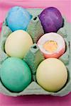 Coloured boiled eggs in egg box